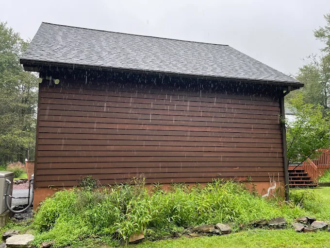 Rainwater pouring off the roof edge of a Northeastern Pennsylvania home that needs gutters