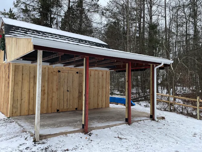 White gutter and downspout repaired on an open pole shed with a red steel frame