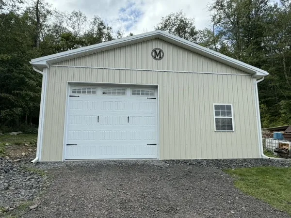 Cream pole-barn garage in Moscow, PA with a white overhead door and new white seamless gutters