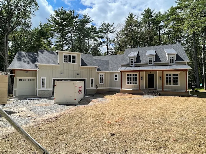 New construction modern farmhouse with shingle roof, standing seam porch roof and white gutters